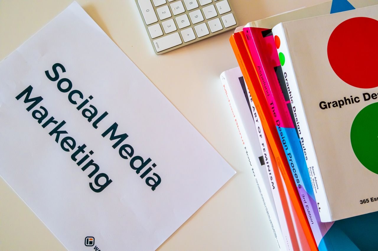 Services A top view of social media marketing text alongside graphic design books and a keyboard.