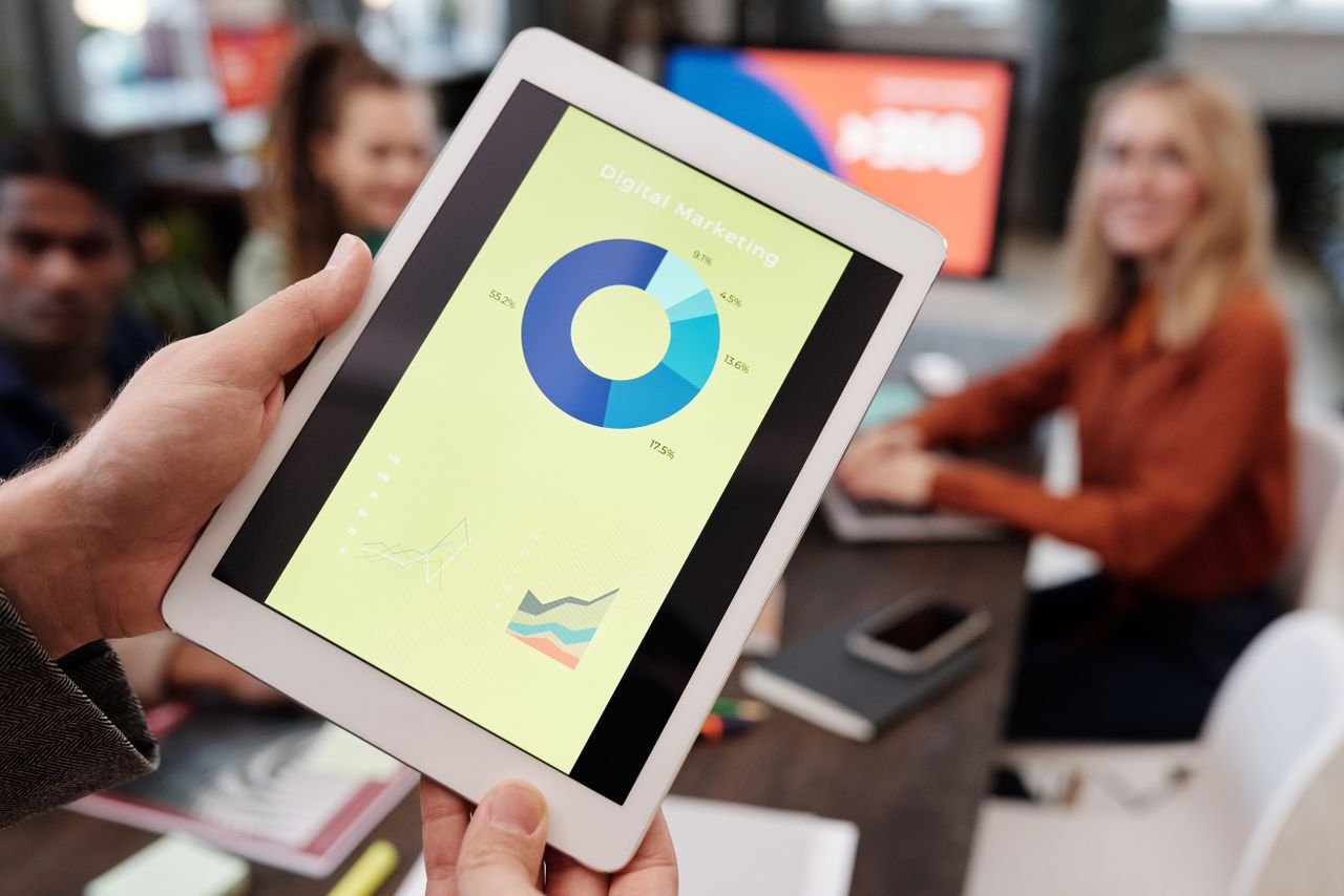 Services Business team reviewing digital marketing statistics on a tablet during an indoor meeting.